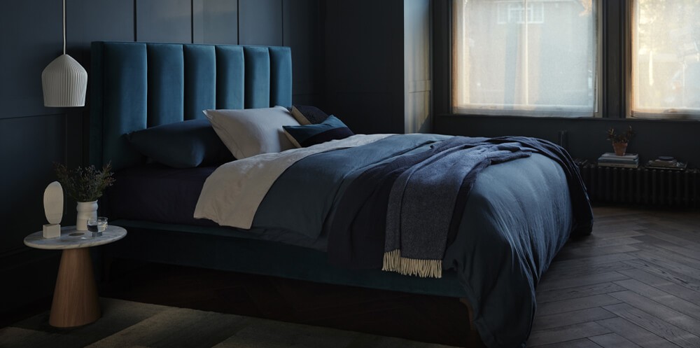 blue interior design trend picturing a dark blue room with bed and dark blue headboard